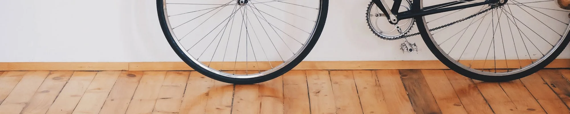 bike leaning against the wall in a room with hardwood flooring