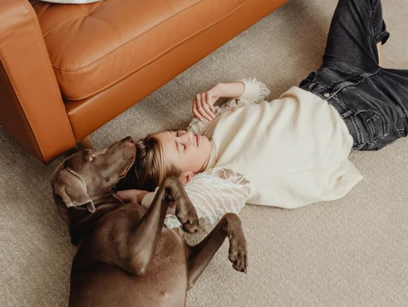 girl and her dog laying, sleeping on carpet flooring